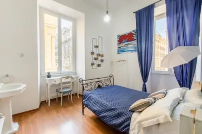 a bedroom with a bed with blue curtains and a sink at Home Of Arts in the Center in Rome
