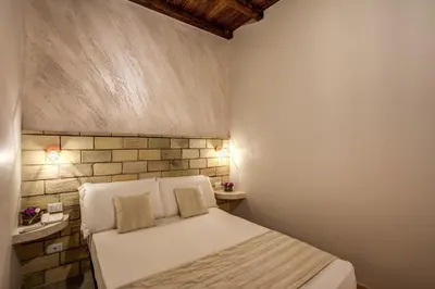 a bedroom with a white bed and a brick wall at Colosseo Accomodation Room Guest House in Rome
