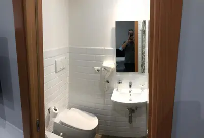 a man taking a picture of a bathroom with a toilet and sink at Rent Rooms Colosseum in Rome