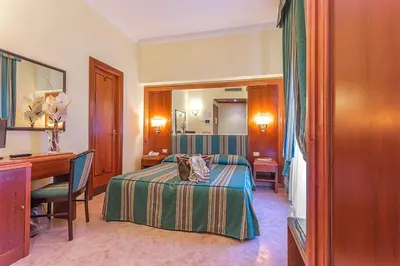 a hotel room with a bed and a desk at Raeli Hotel Lux in Rome