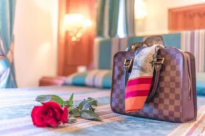 a purple bag sitting on a table next to a rose at Raeli Hotel Luce in Rome