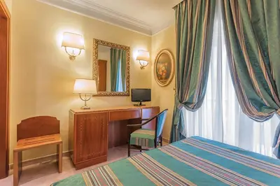 a hotel room with a bed and a desk and a mirror at Raeli Hotel Luce in Rome