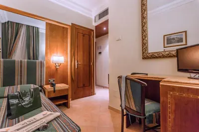 a room with a bed and a desk and a television at Raeli Hotel Luce in Rome