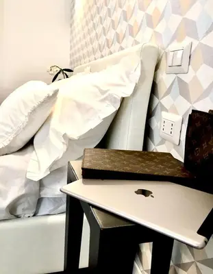 a bed with a nightstand next to a bed with a table at Spagna Rooms in Rome