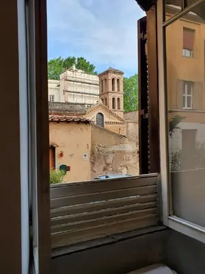 a window with a view of a building and a church at La Roma di Camilla in Trastevere in Rome
