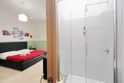 a bathroom with a shower stall and a bed at Dandi Domus in Rome