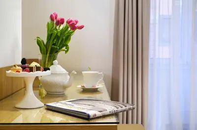 a table with a vase of flowers and a vase of tulips at Magica Luna Boutique Hotel - Roma in Rome