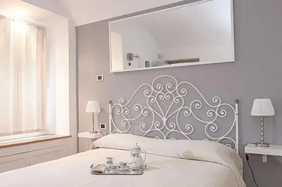 a white bedroom with a bed with a silver headboard at Sweet Rome Colosseo in Rome