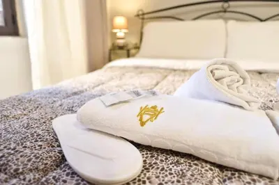 a bed with white towels with a gold crest on it at GuestHouse o Affittacamere Magenta Baylon Suite in Rome