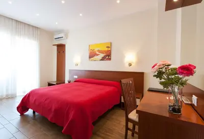 a bedroom with a red bed and a table with a vase of flowers at Alba Romana in Rome