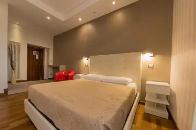 a bedroom with a large bed and a red chair at Borghese Executive Suite in Rome