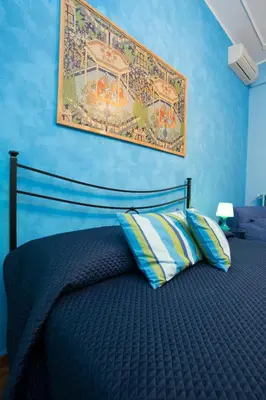 a blue bedroom with a bed with a picture on the wall at Laterano Inn in Rome