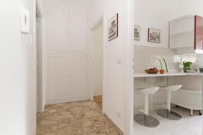 a white kitchen with a counter and a table at Ad Astra Suite in Rome