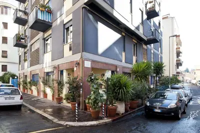 a building with potted plants and cars parked on a street at B&B La Porta in Rome