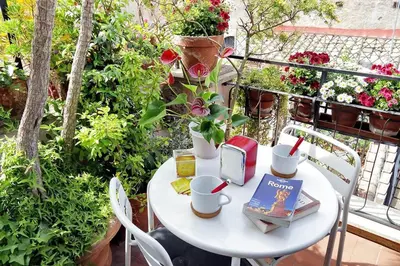 a white table with a book and flowers on a balcony at Scala Luxury Terrace studio in Rome