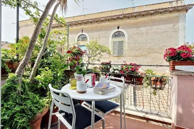 a white table and chairs on a balcony with flowers at Scala Luxury Terrace studio in Rome