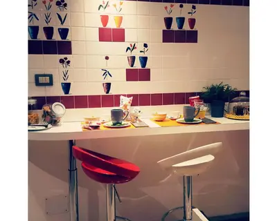 a counter with two stools and a table with cups and plates at B&B Emozioni Romane in Rome
