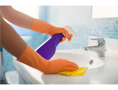 a woman in orange rubber gloves washing a sink at B&B Emozioni Romane in Rome