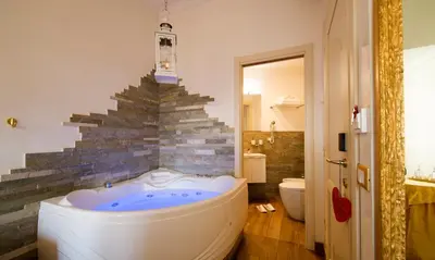 a bath tub in a bathroom with a stone wall at Suites Roma Tiburtina Economy in Rome