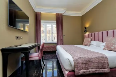 a hotel room with a bed and a desk and a window at BQ House Colosseo Luxury Rooms in Rome