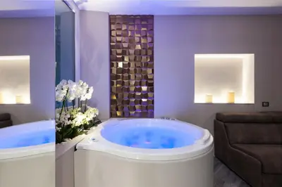 a bathroom with a tub with a chair and flowers at LuMa Suite Via Veneto - Your luxury style 22 in Rome