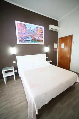 a bedroom with a white bed and a painting on the wall at Hotel Giugiù in Rome