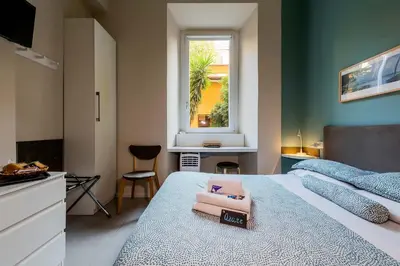 a bedroom with a bed with a desk and a window at Paola Guest House in Rome