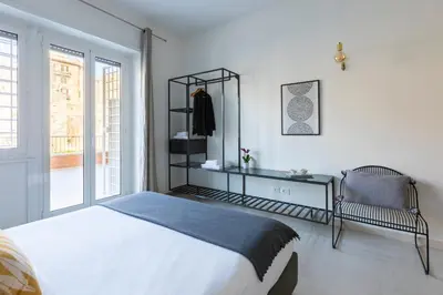 a bedroom with a bed and a chair and a window at ROMAC San Saba 5-Bedroom and Terrace near Ostiense in Rome
