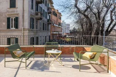 a patio with two chairs and a table and a fence at ROMAC San Saba 5-Bedroom and Terrace near Ostiense in Rome