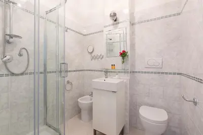 a white bathroom with a toilet and a shower at ROMAC Gianicolo 3-Bedroom Holiday Apartment in Rome