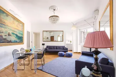a living room with a table and a blue couch at ROMAC Gianicolo 3-Bedroom Holiday Apartment in Rome