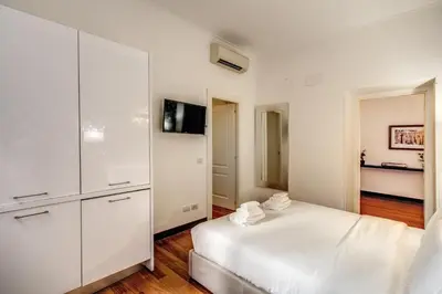 a white bedroom with white cabinets and a bed at Holiday Apartment Bernini Near The Trevi Fountain - 4 Bedroom in Rome