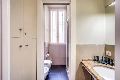 a bathroom with a sink and a toilet and a window at Holiday Apartment Bernini Near The Trevi Fountain - 4 Bedroom in Rome