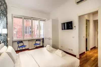 a bedroom with a white bed and two blue chairs at Holiday Apartment Bernini Near The Trevi Fountain - 4 Bedroom in Rome