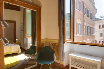 a room with a window and a bed and a chair at ROMAC Baullari Holiday Apartment in Campo de Fiori in Rome