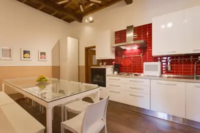 a kitchen with a glass table and white cabinets at ROMAC Baullari Holiday Apartment in Campo de Fiori in Rome