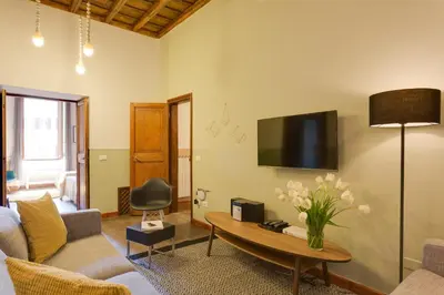 a living room with a table and a tv on the wall at ROMAC Baullari Holiday Apartment in Campo de Fiori in Rome