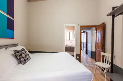 a bedroom with a white bed and a chair at ROMAC Baullari Holiday Apartment in Campo de Fiori in Rome