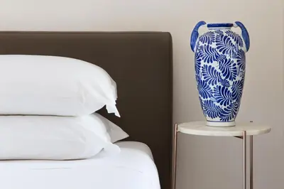 a blue and white vase sitting on a table next to a bed at Experience Collection by ROMAC - Margana Palace in Rome