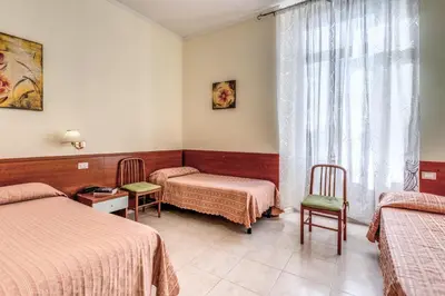 a room with two beds and two chairs and a window at Hotel Katty in Rome