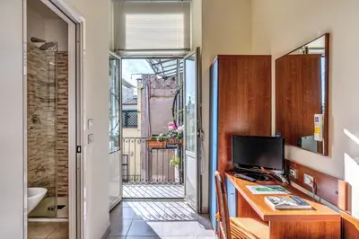 a room with a desk with a television and a bathroom at Hotel Katty in Rome