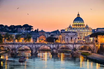 a bridge over a river with a building and a cathedral at Colosseo Rooms Imperial Rome in Rome