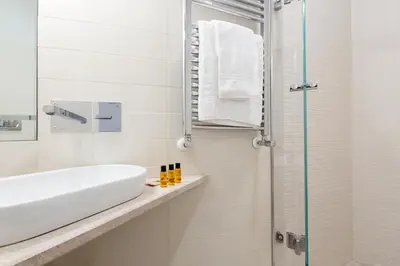 a white bathroom with a sink and a shower at ROMAC Fontanella Borghese Palace in Rome