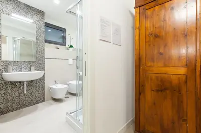 a bathroom with a sink and a toilet and a wooden door at Maison Romana Loft in Rome