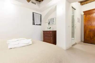 a white bedroom with a large bed and a wooden dresser at Maison Romana Loft in Rome