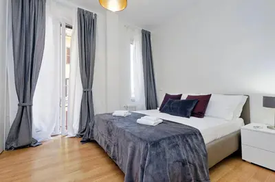 a white bedroom with a large bed and windows at Modern Apartment Quirina 300 mt from Vatican in Rome