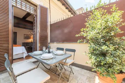 a patio with a table and chairs and a plant at Trevi's Roof Terraces in Rome