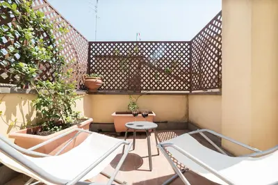 two chairs and a table on a balcony with plants at Trevi's Roof Terraces in Rome