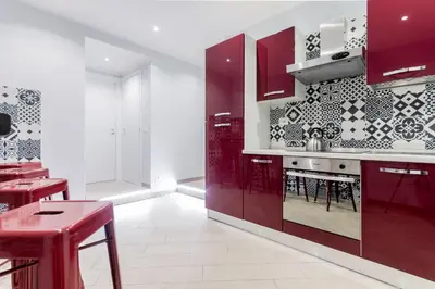 a kitchen with red cabinets and red stools at MARCONI 94 - APARTMENT&PRIVATE ROOMS in Rome