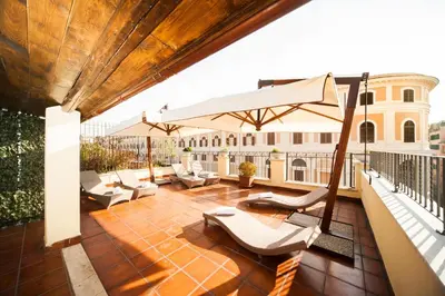a patio with chairs and an umbrella on a balcony at Relais Trevi 95 Boutique Hotel in Rome